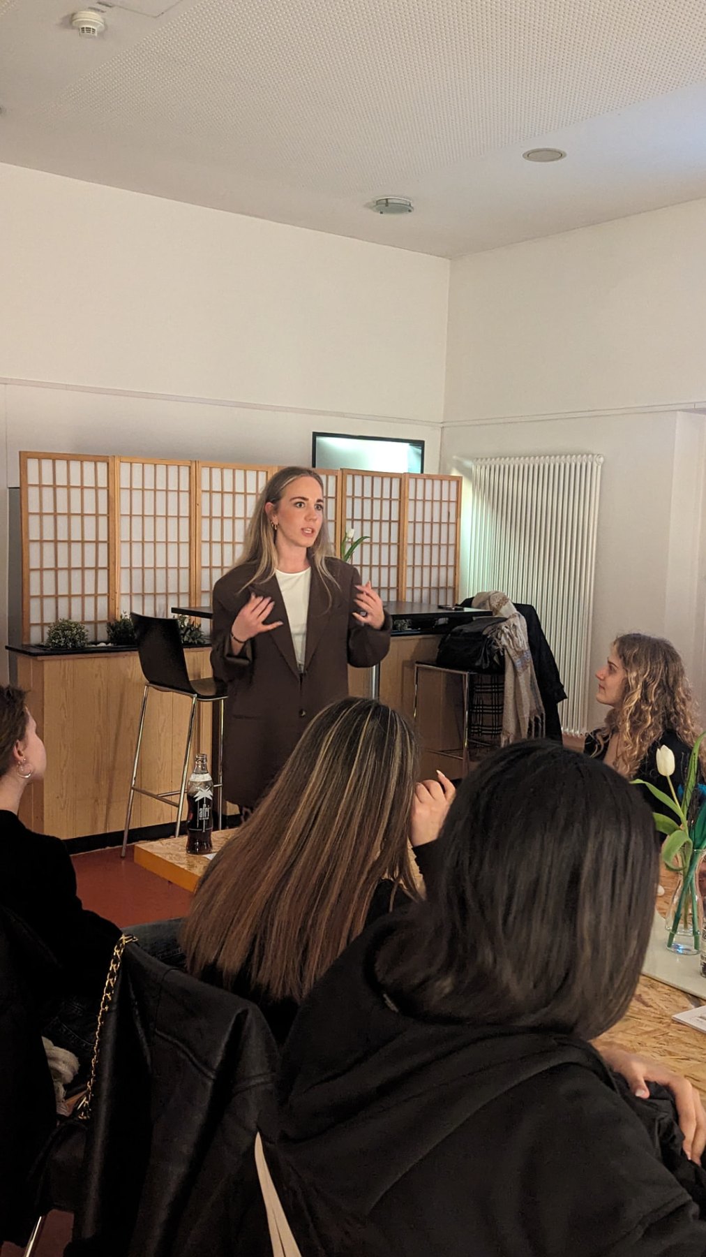 Sabrina spricht vor einer Gruppe bei einem Workshop in hellem Raum